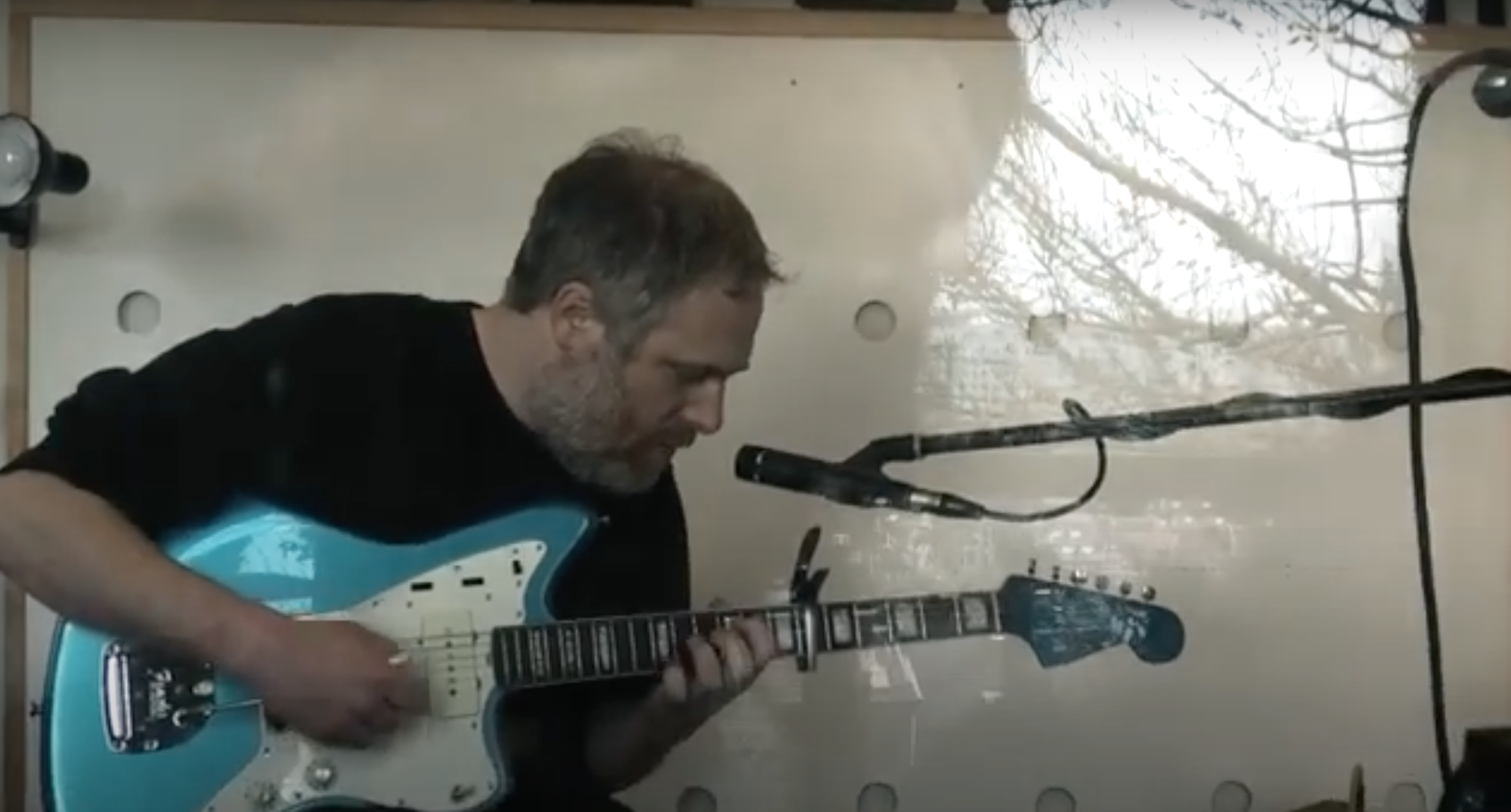 Screenshot from the video showing Ignatz playing guitar, captured from outside a window